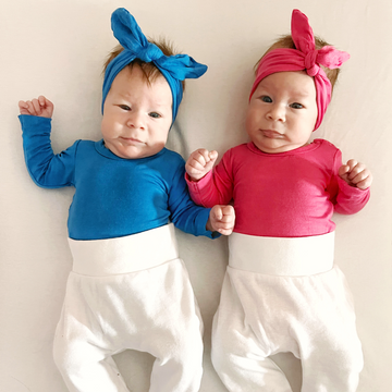 Baby twins wearing LiaaBébé Top Knot Heaband in French Blue and Hot Pink colors.