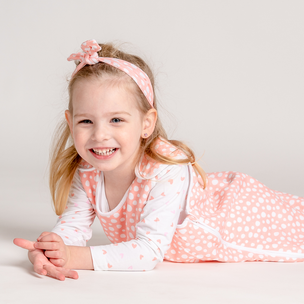 Little baby girl wearing LiaaBébé Top Knot Headband in light pink color with dots.