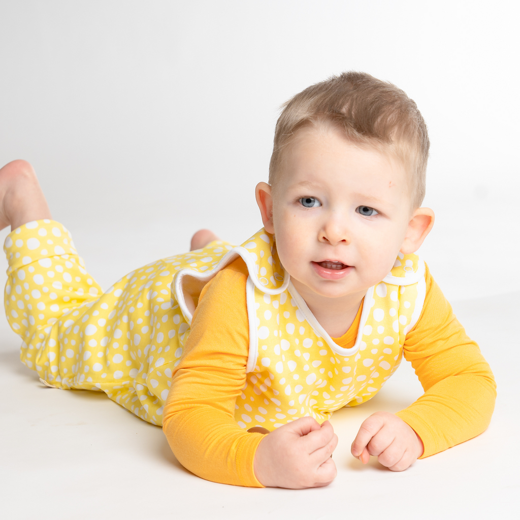 Little baby boy playing in LiaaBébé Toddler Sleeping Bag in Light Yellow color with dots.