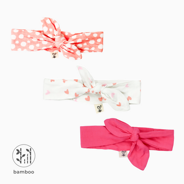Three LiaaBébé Top Knot Headbands in hot pink, light pink with dots and one with pink hearts.